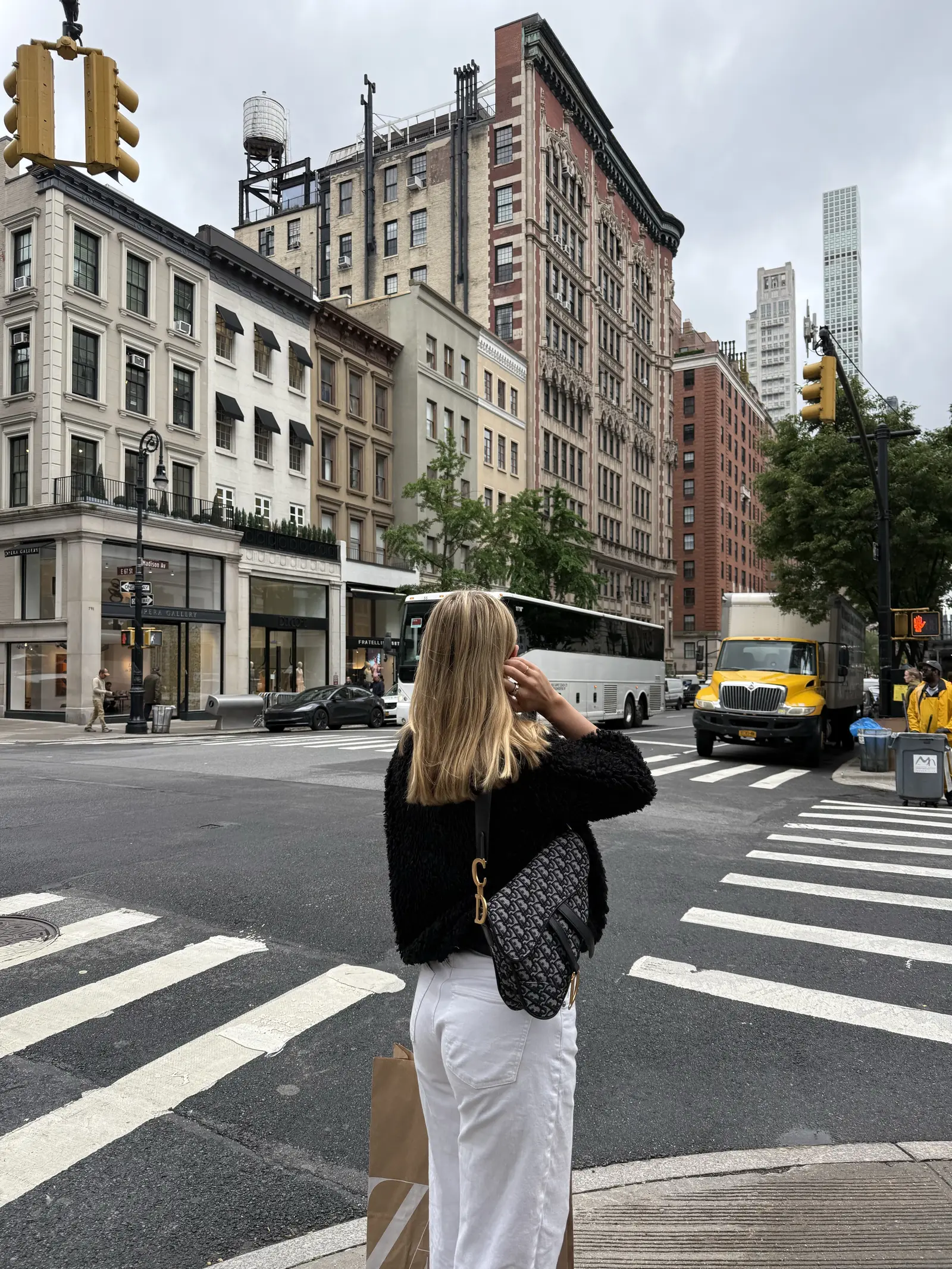 Woman at a city crosswalk surrounded by historic buildings and street traffic